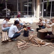 ダッチオーブンで無発酵パンとアクアパッツァの準備中。一斗缶ストーブに火をくべます。